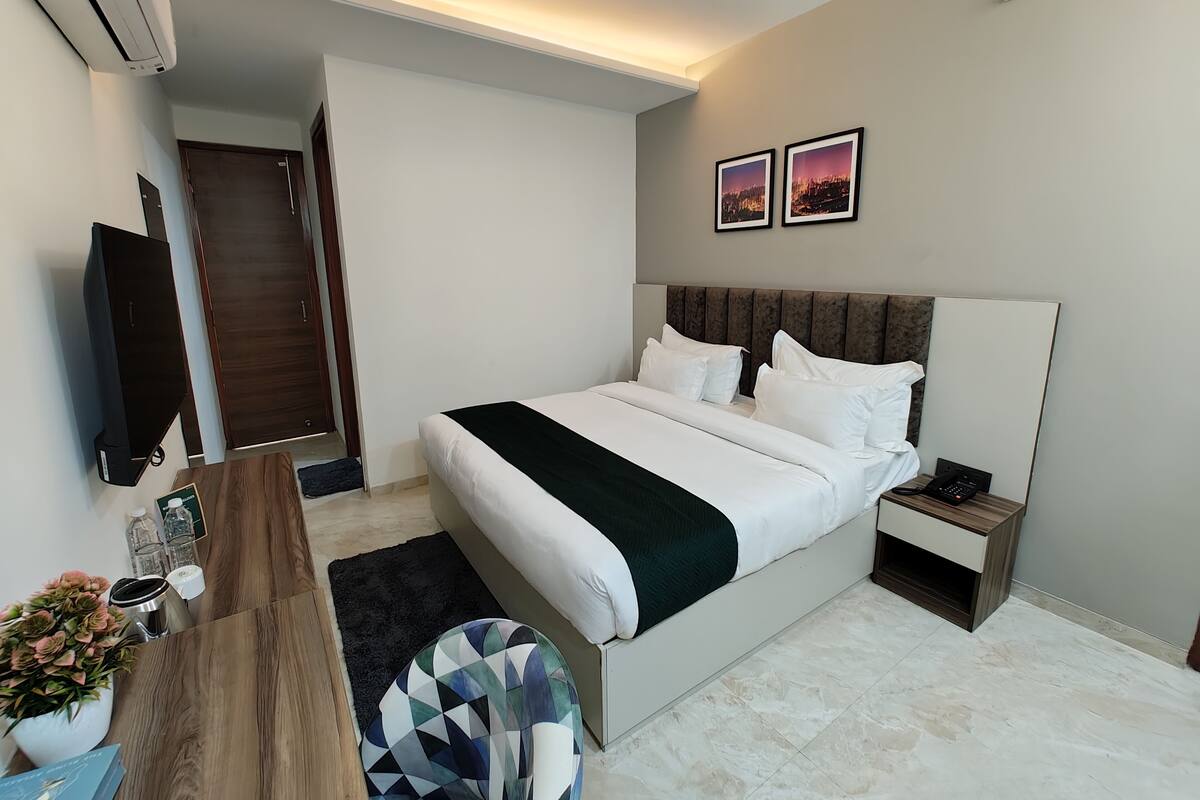 Ein modernes Hotelzimmer mit einem großen Bett, einem Nachttisch und einem Flachbildfernseher.