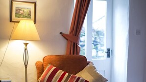 A cozy living room with a wooden ceiling, a lamp, a chair with a striped pillow, and a window with curtains. - Tarn Foot Cottage, Duddon Valley, Lake District  - A rural retreat set deep within the spectacular D (Seathwaite)
