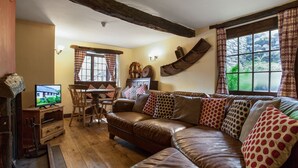 Een gezellige woonkamer met een bruine leren bank, een houten eettafel en een televisie.