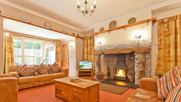 Ein gemütliches Wohnzimmer mit Kamin aus Stein, Ledersofas und einem Fernseher.