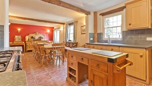 A kitchen with wooden cabinets, a central island, and a dining area with chairs. - Sleeps 12 guests in 6 bedrooms with 2 hot tubs (Coniston)