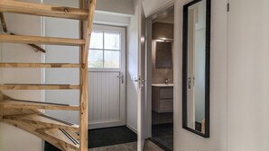 A staircase leading to a door, a bathroom with a sink and mirror, and a window with a view of trees.