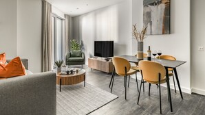 A modern living room with a grey sofa, a coffee table, and a dining area with a table and chairs.