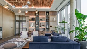 A modern living room with a dark blue sofa, a wooden ceiling, and a large window.