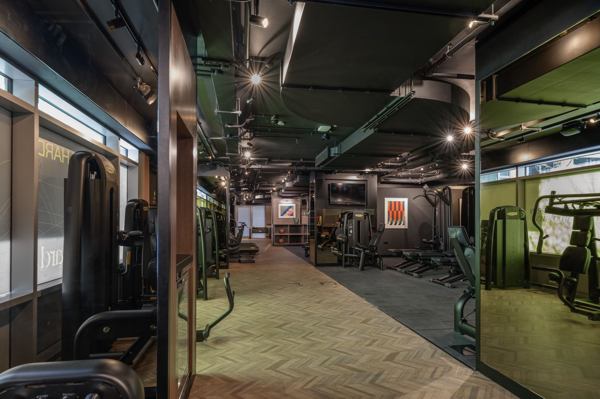 Ein Fitnessstudio mit Trainingsgeräten, einem Spiegel und einer Wand mit einem Logo.