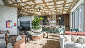 A modern interior with a wooden ceiling, seating areas, a kitchen, and large windows.