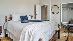 Ein Schlafzimmer mit Bett, Stuhl, Schrank und Spiegel.