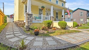 Ein zweistöckiges, gelbes Gebäude mit Veranda, Steinsäulen und einer kleinen amerikanischen Flagge.