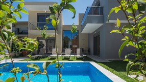 Une maison moderne à deux étages, dotée d’une piscine, d’un espace de détente extérieur et d’une pelouse bien entretenue.