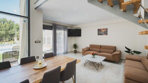 Un salon moderne avec une table à manger en bois, un canapé et un escalier.