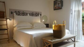 A bedroom with a bed, a bedside table with a basket, a wall-mounted mirror, and a ladder against the wall.