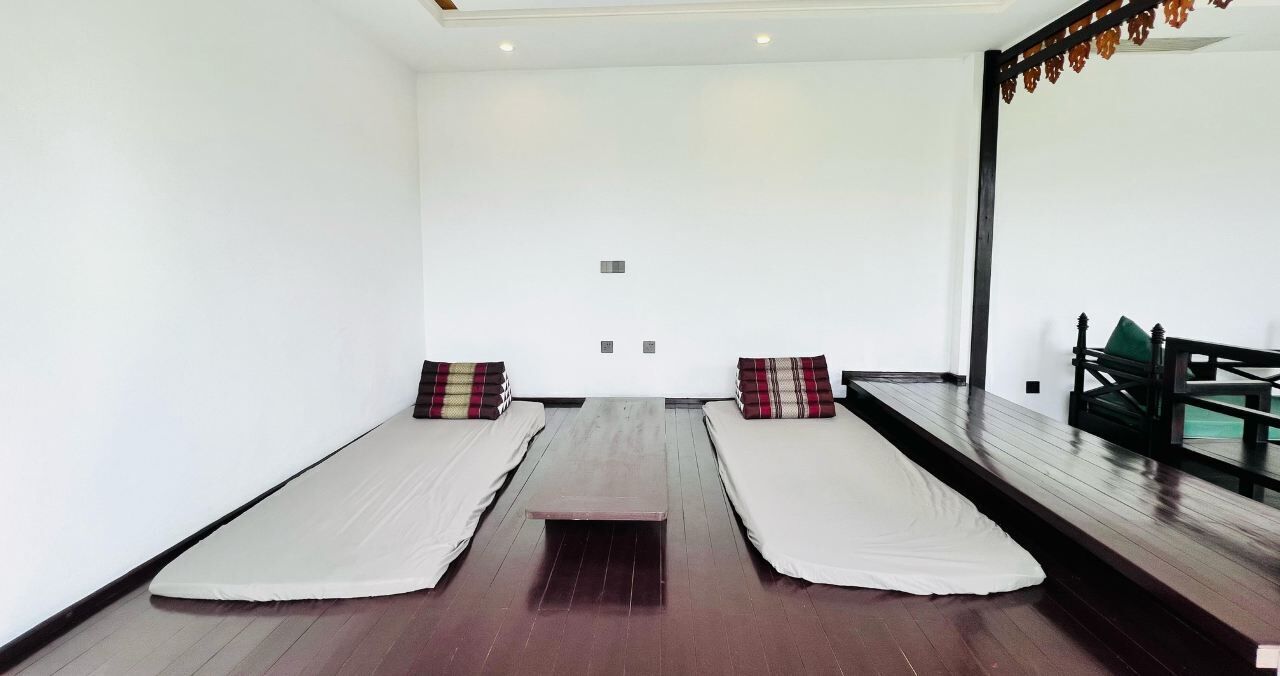 A room with two beds, a wooden floor, and a large mirror on one wall.
