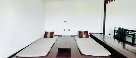 A room with two beds, a wooden floor, and a large mirror on one wall.