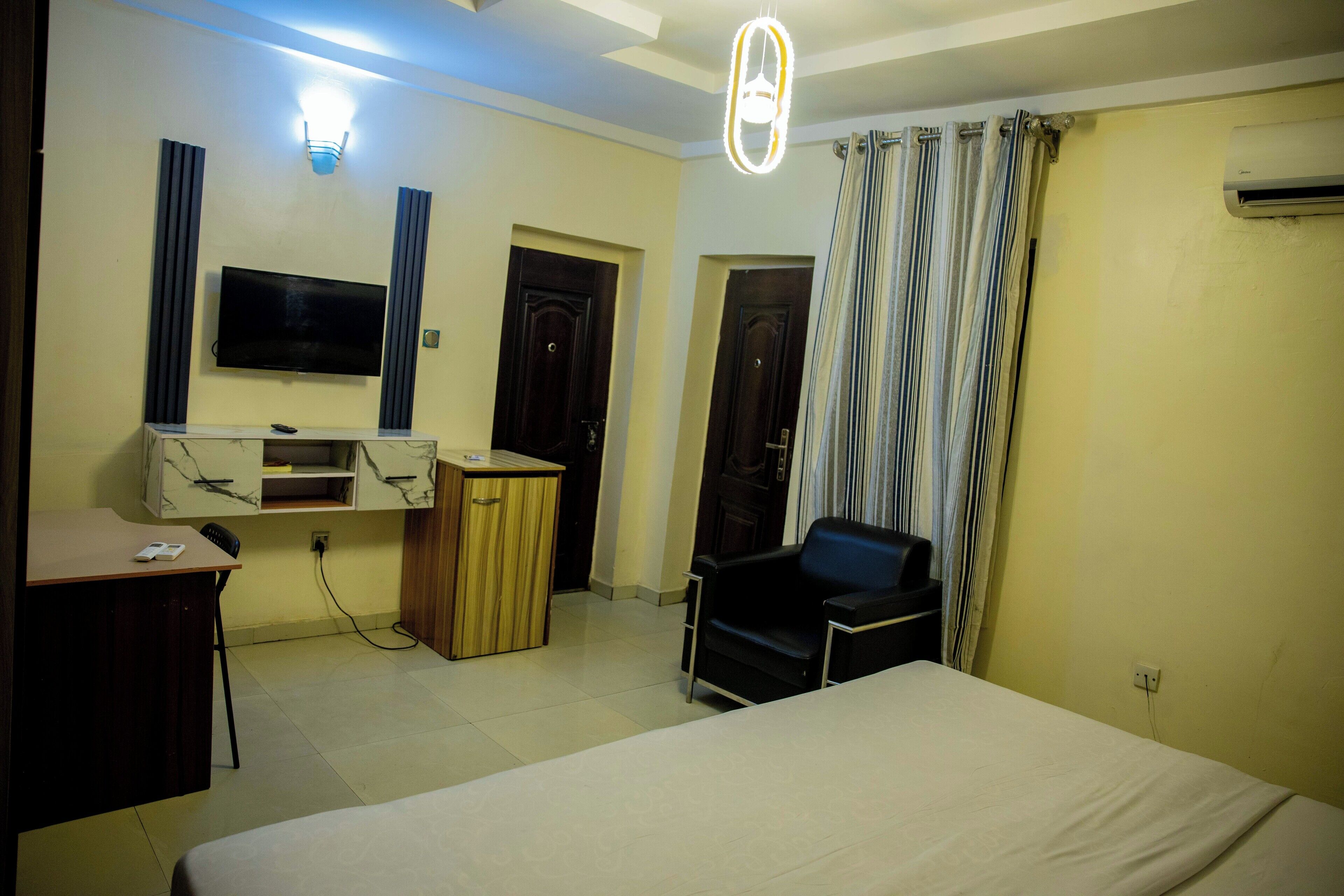 A hotel room with a bed, a desk, a chair, a TV, and a curtain.