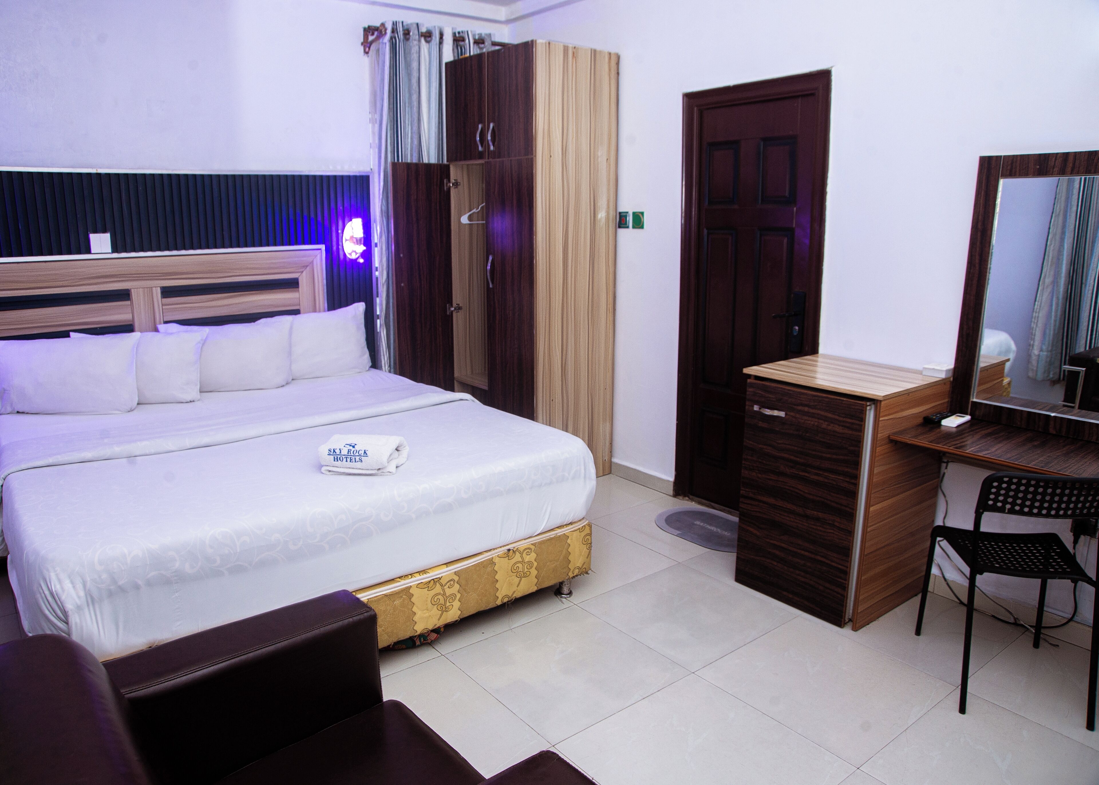 Una habitación de hotel con cama, escritorio, silla, armario y puerta.