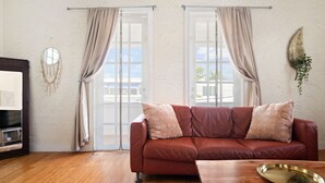 A living room with a brown leather sofa, a wooden coffee table, and a patterned rug. - Breezy beach apt, steps to the sand! Full AC + Generator (Santurce)