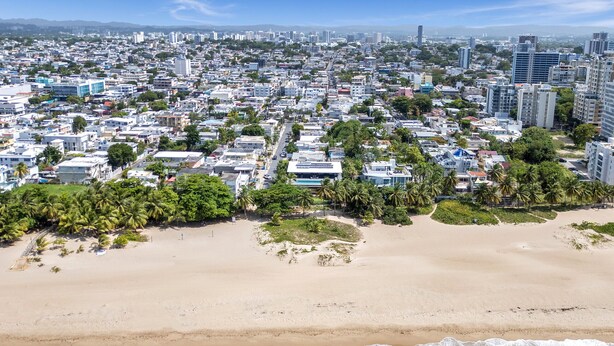 A coastal cityscape with a wide sandy beach and turquoise waters. - Breezy beach apt, steps to the sand! Full AC + Generator (Santurce)