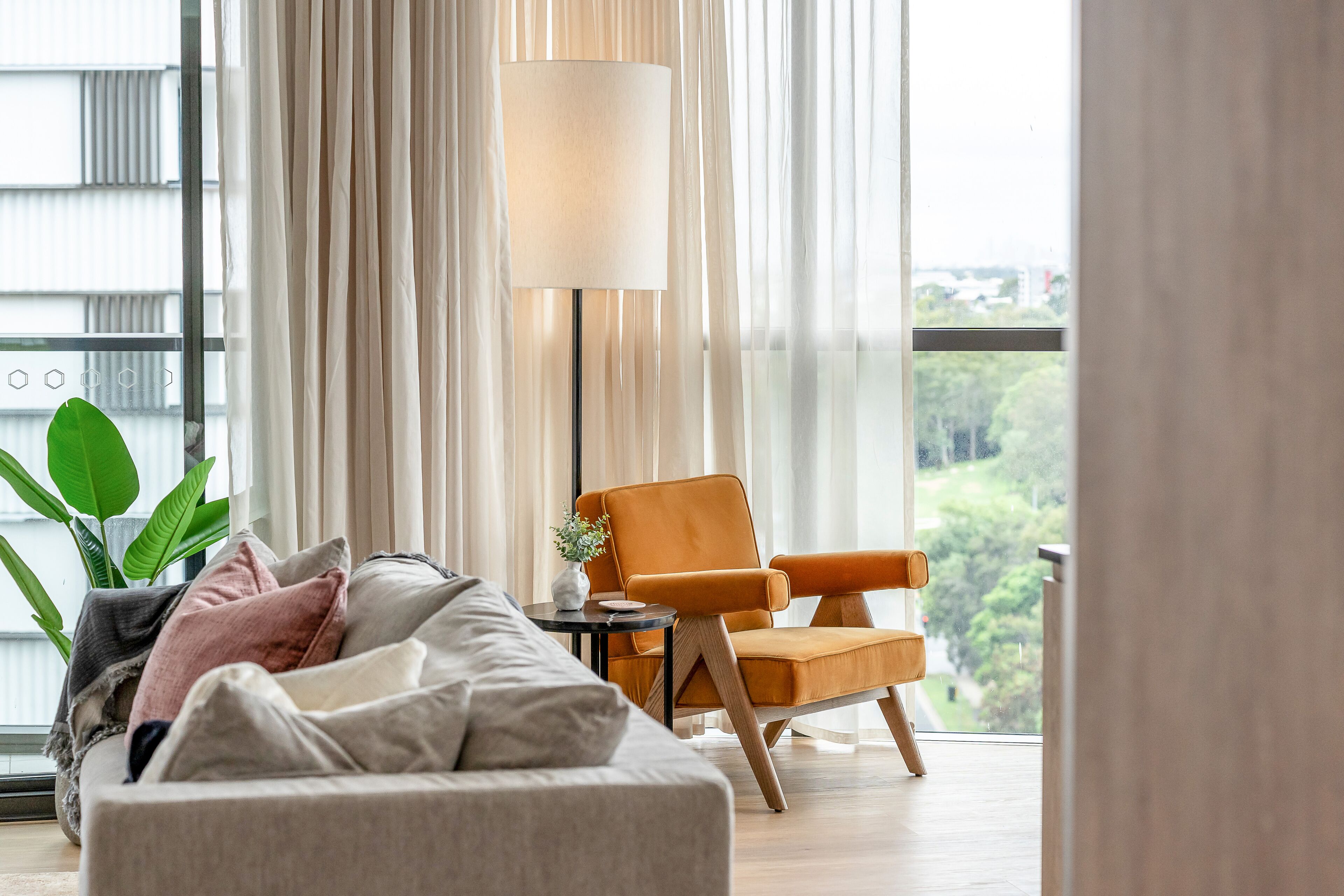A modern living room with a sofa, a side table, a lamp, and a chair.
