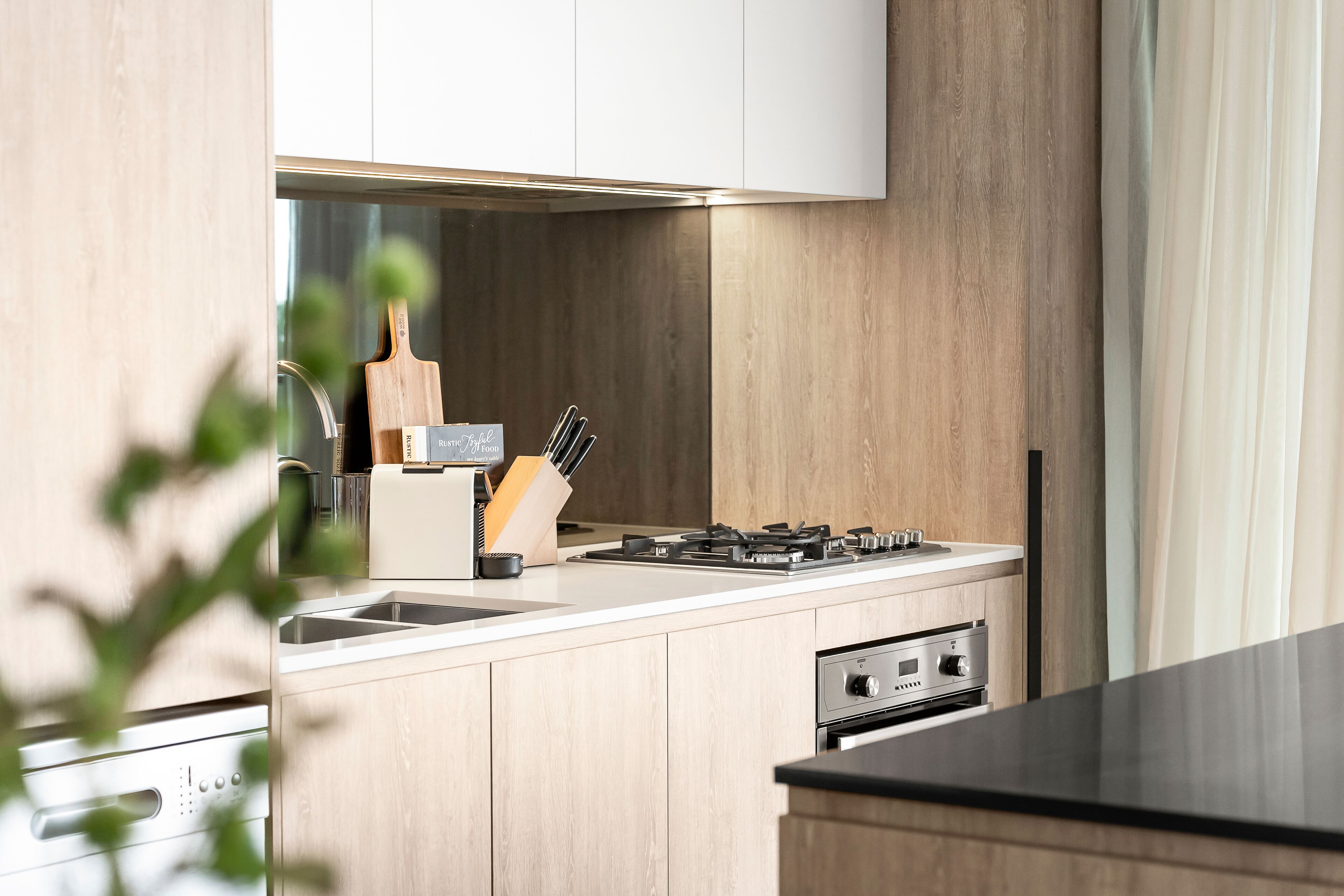 A modern kitchen with wooden cabinets, a gas stove, a built-in oven, and a sink.