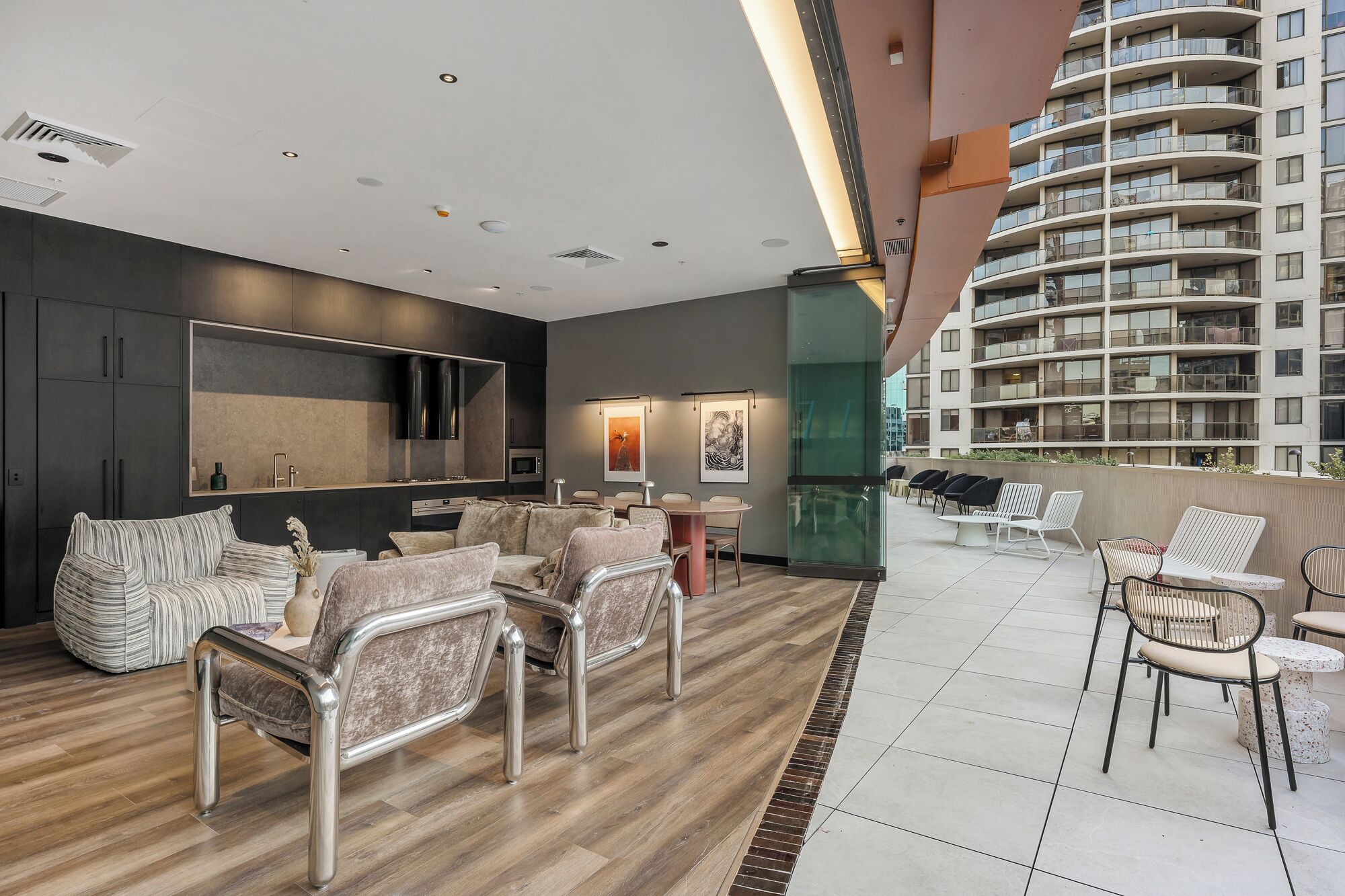 A modern interior with a dining area, sofas, and a view of a high-rise building.