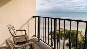 Un balcon donnant sur la plage, une chaise et une horloge au mur.