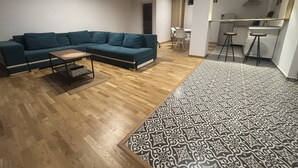 Ein modernes Wohnzimmer mit einer Eckcouch, einem Couchtisch und einem gemusterten Teppich.