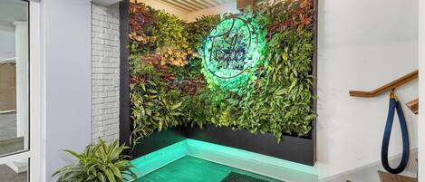 A modern interior with a green wall, a neon sign, and a wooden staircase.