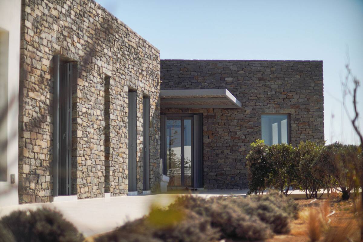 A modern stone building with large windows and a flat roof.