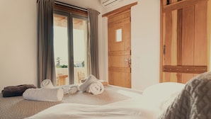 A hotel room with a bed, a wooden wardrobe, and a window with curtains. - Anapnoe Resort by ParosKite (Paros)