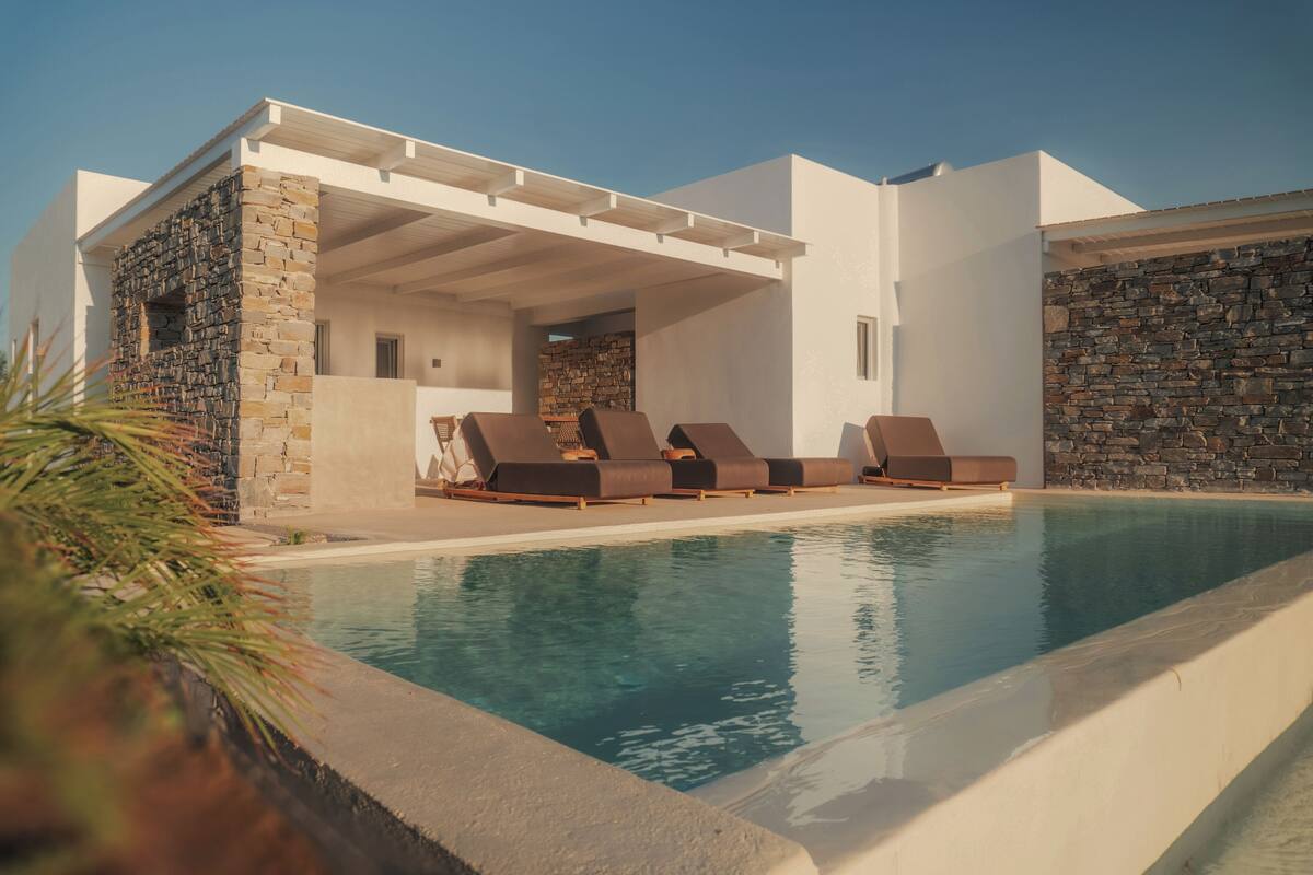A modern poolside area with lounge chairs and a stone wall.