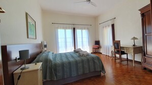 A bedroom with a bed, bedside table, lamp, desk, chair, and curtains. - Villa Flangini (Asolo)