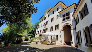 A building with a courtyard, outdoor seating, and a staircase leading to the entrance. - Villa Flangini (Asolo)
