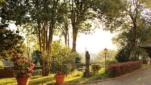 A cobblestone pathway in a park with potted plants and a statue. - Villa Flangini (Asolo)