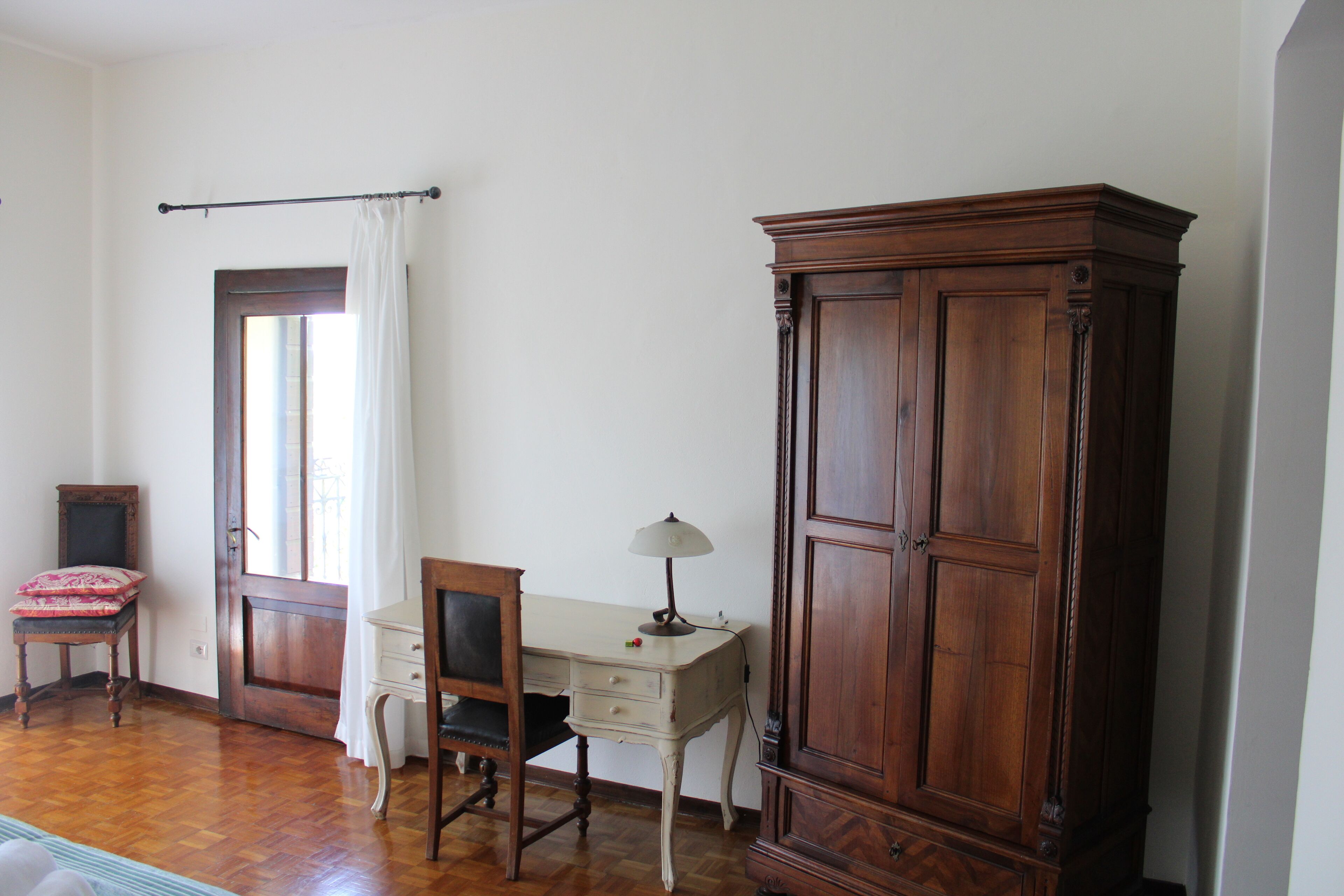 A room with a wooden desk, a chair, a cabinet, and a window with curtains.