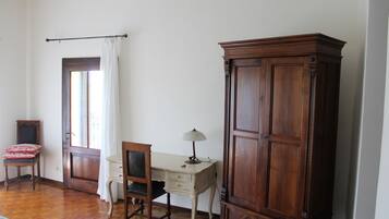 A room with a wooden desk, a chair, a cabinet, and a window with curtains.
