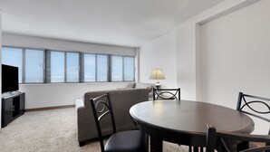 Een moderne hotelkamer met een ronde eettafel, twee stoelen, een bank, een televisie en een lamp.