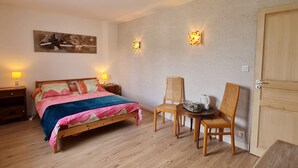 Une chambre à coucher comprenant un lit, des tables de chevet, une chaise, une petite table avec une bouilloire et une porte.