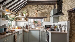 Una cocina rústica con paredes de piedra, vigas de madera y una ventana con vistas.