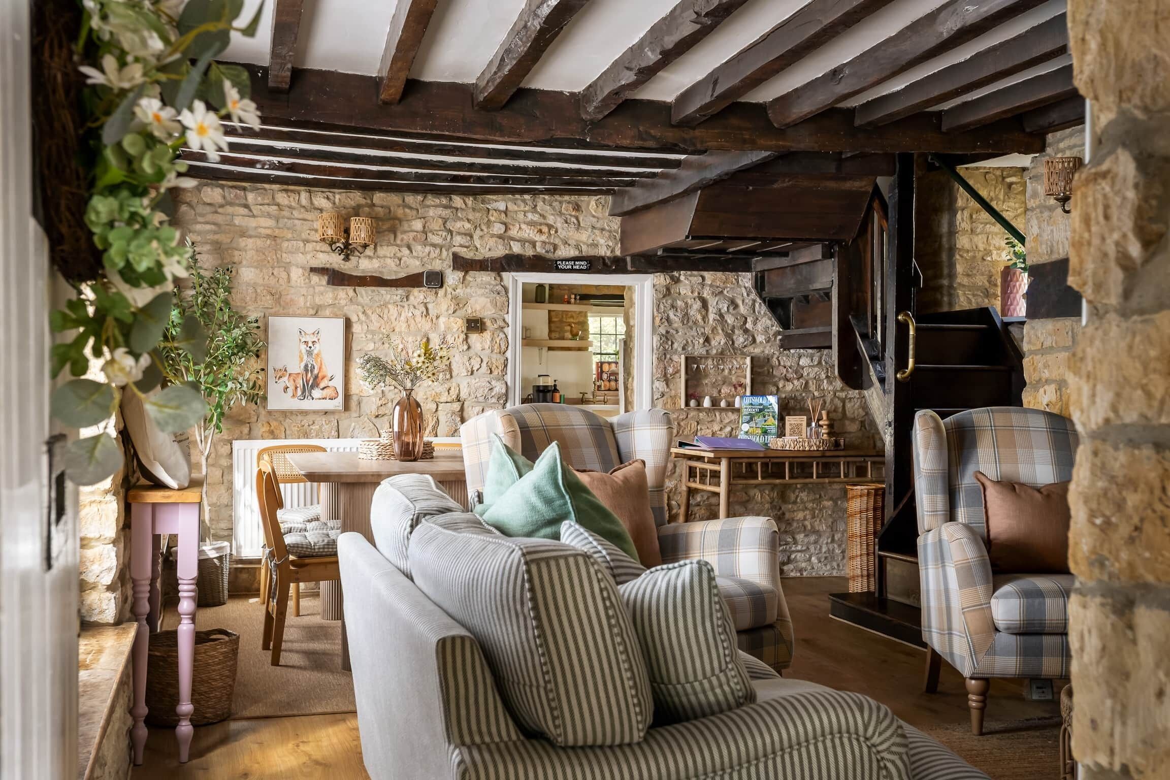 A rustic interior with stone walls, wooden beams, a fireplace, and a dining area.