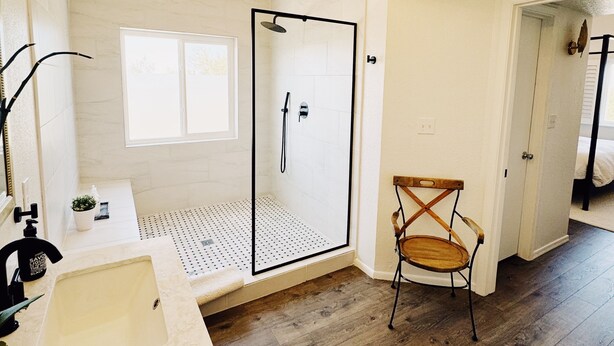 Une salle de bain moderne avec une douche, un lavabo et une chaise.