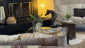 Un salon moderne avec une cheminée en marbre noir, une table basse en verre et un canapé gris.