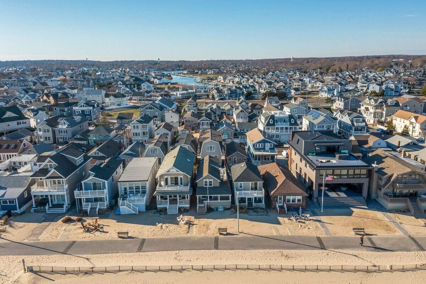 Un quartier résidentiel avec des maisons, une plage et une étendue d’eau en arrière-plan.