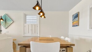 Een eethoek met een houten tafel, witte stoelen en hanglampen.