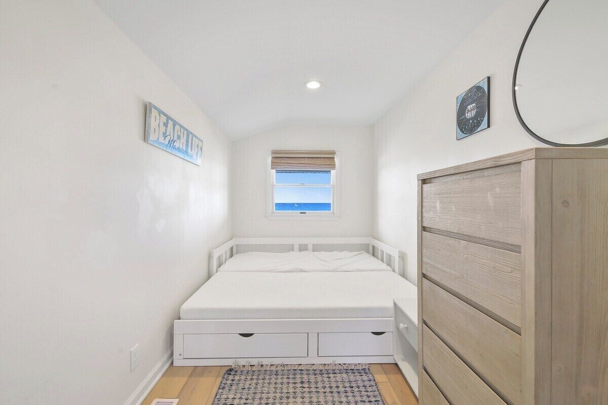 Een compacte, netjes ingerichte slaapkamer met een bed, een raam, een kledingkast en een klein wandplankje.