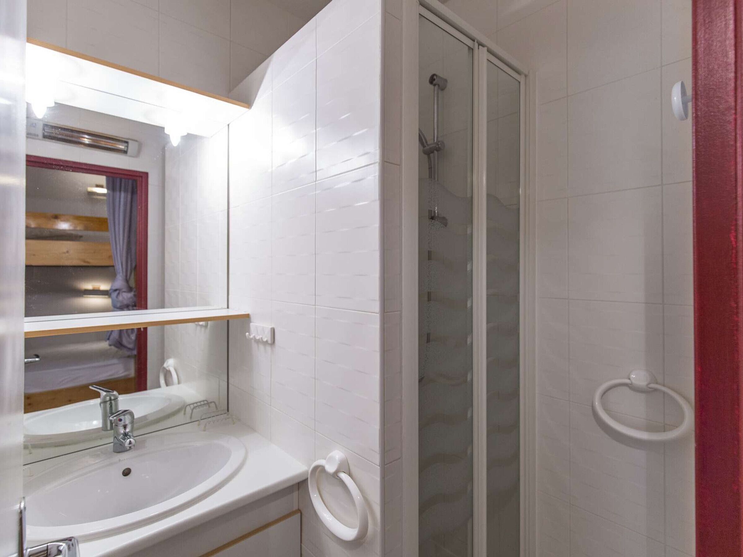 A bathroom with a white sink, mirror, and glass shower enclosure.