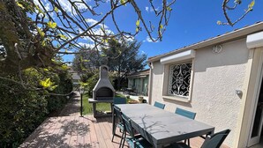 A patio with a table and chairs, a stone oven, and a garden path. - Quiet villa in Balaruc with aircon and parking (Balaruc-les-Bains)