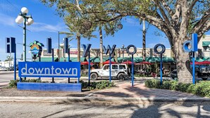 A sign for 'Downtown' with a clear view of the street, palm trees, and outdoor seating areas of cafes. - Hollywood Beach Getaway ~ Executive Studio Suite (Hollywood)