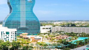A modern building with a guitar-shaped design, surrounded by palm trees and a swimming pool. - Hollywood Beach Getaway ~ Executive Studio Suite (Hollywood)