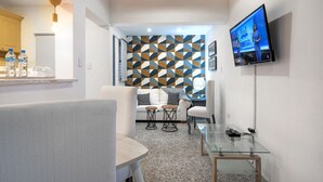 A modern hotel room with a dining area, a TV mounted on the wall, and a geometric patterned wall. - Escape Apartment in Gazcue Close to Colonial Zone (Santo Domingo)