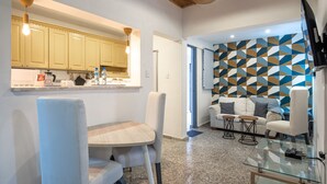 A modern kitchen with light yellow cabinets, a dining area with a round table and chairs, and a living room with a patterned wall and seating. - Escape Apartment in Gazcue Close to Colonial Zone (Santo Domingo)
